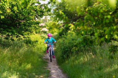9 yaşlarında küçük bir kız bisiklete biniyor. Aktif yaşam tarzı. Okul yaz tatili.