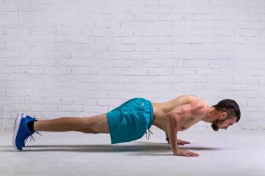 Şortlu bir sporcu nasıl şınav çekileceğini gösterir. Aktif yaşam tarzı, spor.