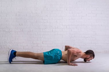 Şortlu bir sporcu nasıl şınav çekileceğini gösterir. Aktif yaşam tarzı, spor.