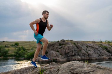 Taşların üzerinde koşan erkek koşucu, boş alanın kopyası. Aktif yaşam tarzı, atletizm.