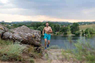 Taşların üzerinde koşan erkek koşucu, boş alanın kopyası. Aktif yaşam tarzı, atletizm.
