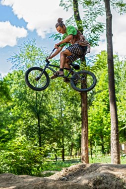 Bir BMX bisikletçisi uçuş sırasında bir numara yapıyor. Sıçrama tahtasından bisiklete atlamak. Ekstrem bisiklet.