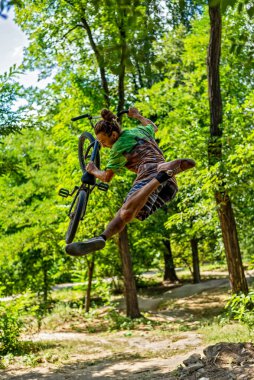Bir BMX bisikletçisi uçuş sırasında bir numara yapıyor. Sıçrama tahtasından bisiklete atlamak. Ekstrem bisiklet.