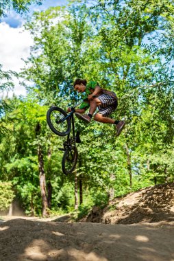 Bir BMX bisikletçisi uçuş sırasında bir numara yapıyor. Sıçrama tahtasından bisiklete atlamak. Ekstrem bisiklet.