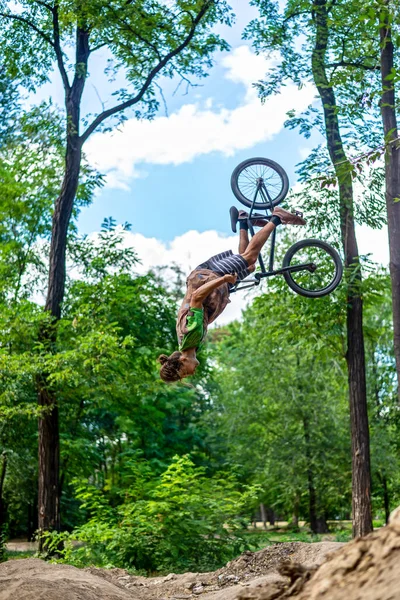 A bmx cyclist doing a back flip stunt in flight. Jump on a bike from a springboard. Extreme cycling.