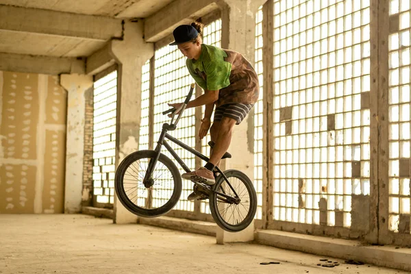 Terk edilmiş bir fabrika binasında atlayış yapan bir BMX bisikletçisi. Aşırı bisiklet sürme. Şehir gezisi.