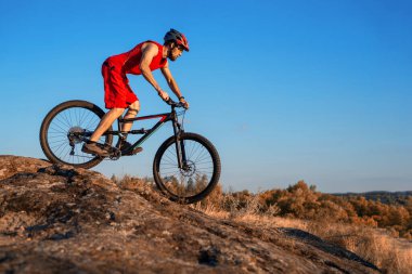 Bir bisikletçi taşların üzerinden mavi gökyüzüne doğru gidiyor, boş alanın kopyası. Aktif yaşam tarzı, bisikletçilik. MTB.