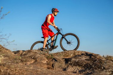 Bir bisikletçi taşların üzerinden mavi gökyüzüne doğru gidiyor, boş alanın kopyası. Aktif yaşam tarzı, bisikletçilik. MTB.