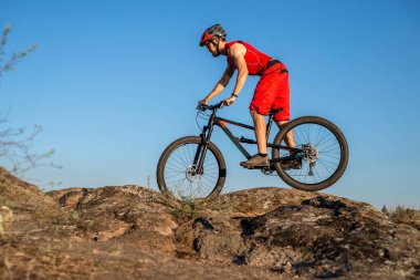 Bir bisikletçi taşların üzerinden mavi gökyüzüne doğru gidiyor, boş alanın kopyası. Aktif yaşam tarzı, bisikletçilik. MTB.