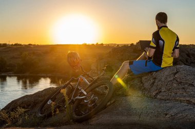 Dışarıda dizüstü bilgisayarla çalışan serbest çalışan bir erkek. Bisikletçi uzaktan çalışıyor..