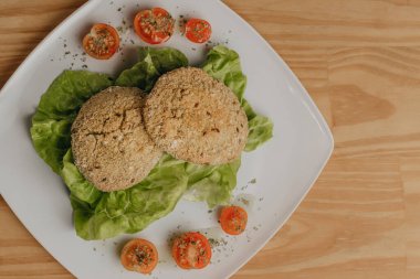 Plato de comida sana sobre mesa de madera. Vista Amirliği. Dieta de Milanesas de quinoa rellenas de espinaca y queso, acompaadas de lechuga y tomates cherry. Dieta kurtarılabilir.