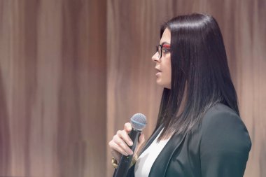 Elinde mikrofonla konferansta ya da seminerde konuşan güzel bir iş kadını..