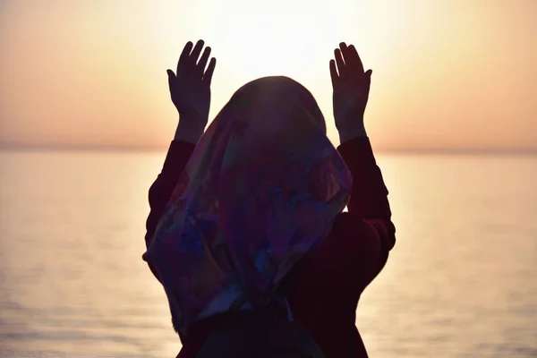 Mulher muçulmana orando no navio orando ao pôr do sol com as mãos para cima — Fotografia de Stock