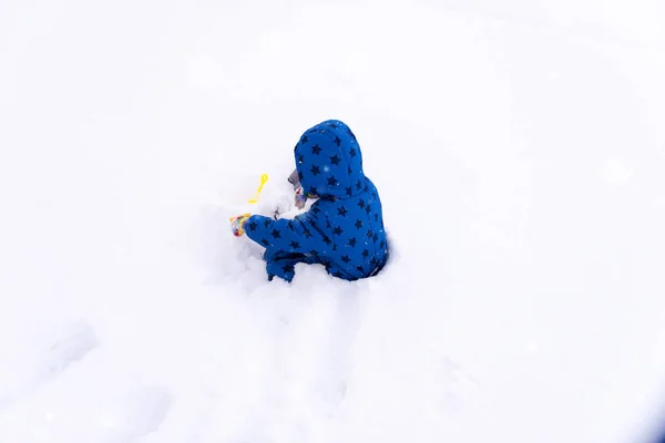 Çocuk, üç yaşında kışlık kıyafetler içinde kar ile oynarken. — Stok fotoğraf
