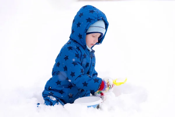 Niño, niño de tres años con ropa de invierno jugando con la nieve . —  Fotos de Stock