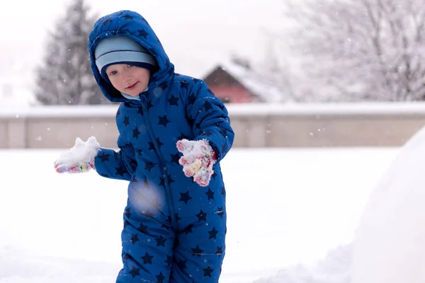 Child, three years old boy in winter clothes playing with snow. — Stock Photo, Image