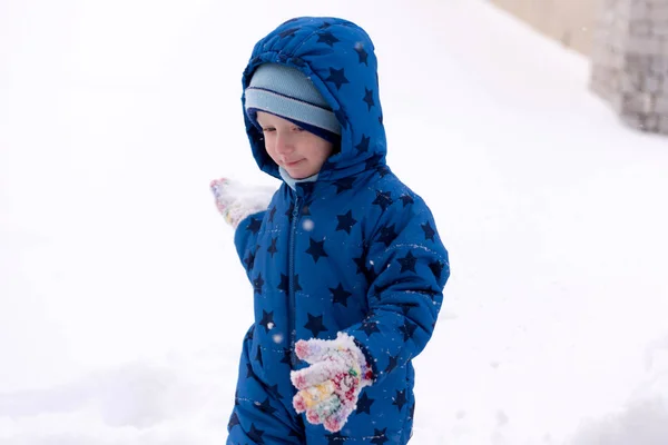 Niño, niño de tres años con ropa de invierno jugando con la nieve . — Foto de Stock