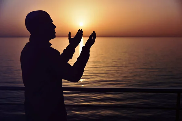 Muslim prayer in the ship praying at sunset with hands up. A sil — Stock Photo, Image