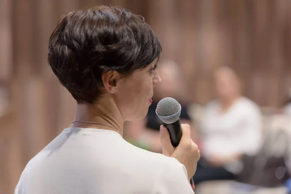 Beautiful business woman with microphone in her hand speaking at — Stock Photo, Image