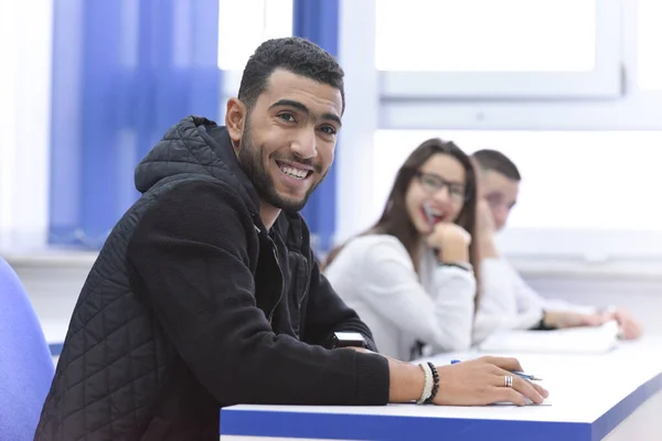 Univerzitní studentka ve třídě sedí za stolem a obrací se k — Stock fotografie