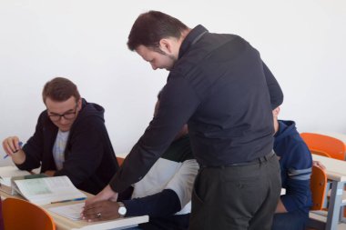 Erkek profesör öğrencilere ders veriyor ve onlarla iletişim kuruyor.
