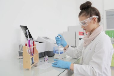 Laboratuvarda test tüpleriyle çalışan genç kadın laboratuvar bilim adamı.