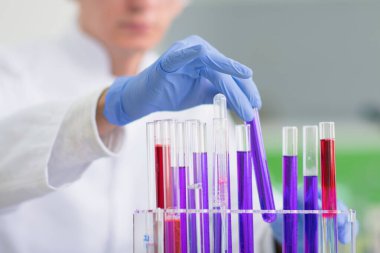 Laboratuvarda test tüpleriyle çalışan genç bir bilim adamı.