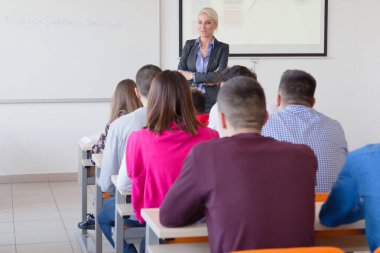 Çekici kadın profesör öğrencilere ve öğrencilere ders veriyor.
