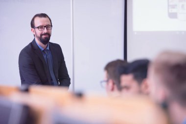 Modern okul sınıfında bir grup öğrenci profesörle birlikte okuyor.