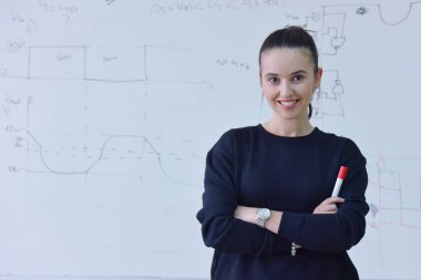 Elinde kalemle önünde duran genç bir kız öğrenci. 