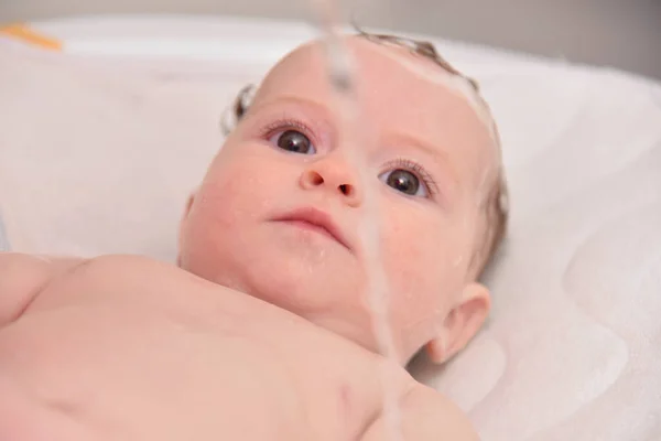 Hübsches drei Monate altes Mädchen, das von seiner Mutter zu Hause gebadet wird, europäisches Kind. — Stockfoto