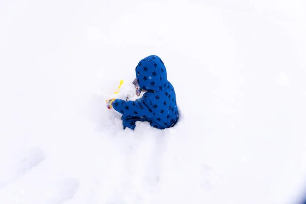 Kind, drie jaar oud jongen in winterkleren spelen met sneeuw. — Stockfoto