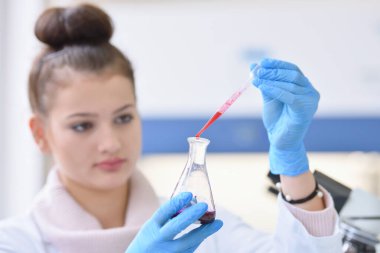 Laboratuvarda test tüpleriyle çalışan genç kadın laboratuvar bilim adamı.