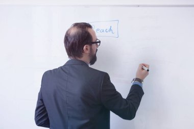 İş yerindeki erkek öğretmenin portresi. Erkek profesör öğrencilere açıklama yapıyor, tahtada kararlılıkla yazıyor..