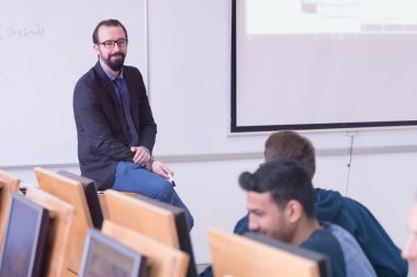 Modern okul sınıfında bir grup öğrenci profesörle birlikte okuyor.