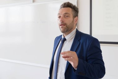 Erkek profesör öğrencilere ders veriyor ve onlarla iletişim kuruyor.