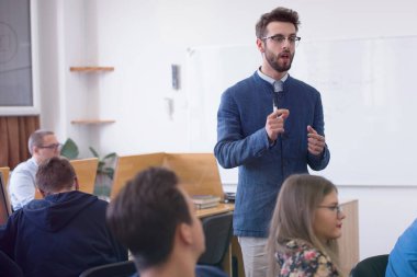 Modern okul sınıfında bir grup öğrenci profesörle birlikte okuyor.