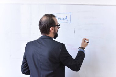 Erkek profesör öğrencilere ders veriyor ve onlarla iletişim kuruyor.