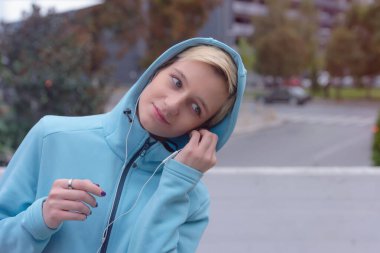 Genç bayan koşucu şehir caddesinde koşuya hazırlanıyor. Formda olmak için çok çalışmak gerekir. Şehir sporu konsepti. Spor kıyafetleriyle egzersiz yapan genç bir bayan..