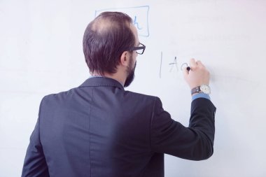 İş yerindeki erkek öğretmenin portresi. Erkek profesör öğrencilere açıklama yapıyor, tahtada kararlılıkla yazıyor..