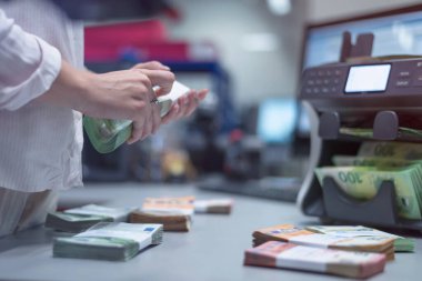 Banka çalışanları banka kasasında para sıralayıp sayıyor.
