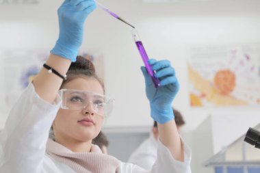 Laboratuvarda test tüpleri ve mikroskopla çalışan iki genç kadın ve erkek bilim adamı.,