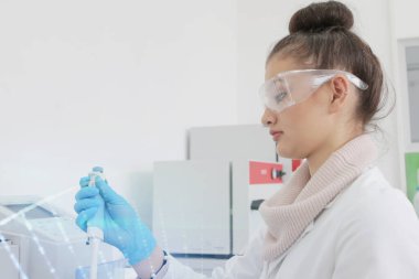 Laboratuvarda test tüpleriyle çalışan genç kadın laboratuvar bilim adamı.