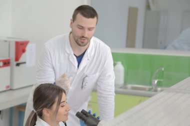 Laboratuvarda çalışan iki genç kadın ve erkek bilim adamı.