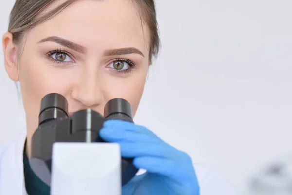 Young female male scientist looking through a microscope in a la — Stock Photo, Image