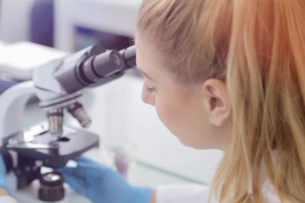 Νεαρή γυναίκα επιστήμονας που κοιτάζει μέσα από ένα μικροσκόπιο στο a la — Φωτογραφία Αρχείου