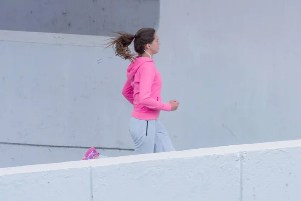 Kapüşonlu genç bayan koşucu şehir sokaklarında koşuyor. — Stok fotoğraf