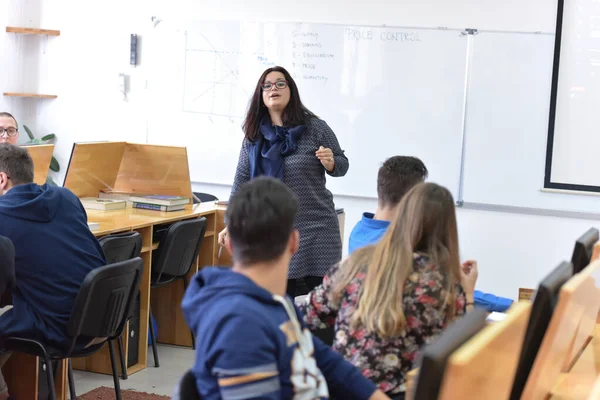 Γυναίκα καθηγήτρια εξηγήσει το μάθημα στους μαθητές και να αλληλεπιδρούν με ου — Φωτογραφία Αρχείου