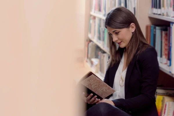 大人の若い女性学生図書館で本を読んで、座って — ストック写真