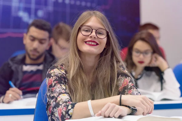 Universitaire vrouwelijke student in de klas zit aan haar bureau wenden tot s — Stockfoto